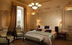 Luxurious bedroom in Casa Gangotena, featuring elegant decor, a king-sized bed with plush bedding, and stylish armchairs, showcasing the hotel's sophisticated ambiance in Quito, Ecuador.