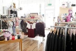 Boutique clothing store interior featuring racks of fashionable apparel, including dresses and tops, with a bright, inviting atmosphere.