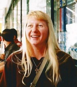 Smiling woman with long blonde hair in a casual setting, reflecting a travel-related experience for ExploreTraveler.