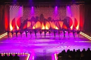 Colorful stage performance with dancers in silhouette against a vibrant backdrop, showcasing Cancun's lively entertainment scene.