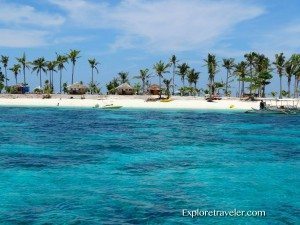 Caribbean beach scene featuring clear turquoise waters, white sandy shore, and palm trees, representing travel experiences on Pandanon Island in the Philippines.