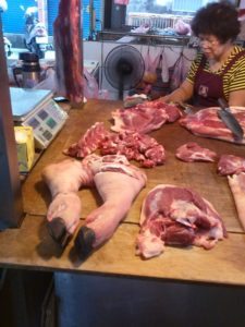 Butcher preparing various cuts of meat on a wooden table, showcasing charcuterie ingredients for culinary inspiration.
