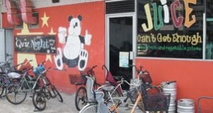 Panda mural on red wall of juice shop with bicycles parked outside, reflecting Chinese wildlife and cultural theme relevant to travel experiences.