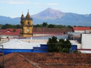 Colorful rooftops with a clock tower in the foreground and a mountain backdrop, showcasing a vibrant travel destination.