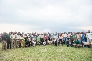 Group of diverse individuals standing together on grassy field, showcasing community engagement in outdoor event related to travel and nature.