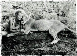 Woman embracing a lion on a rocky surface, symbolizing themes of freedom and exploration in travel.