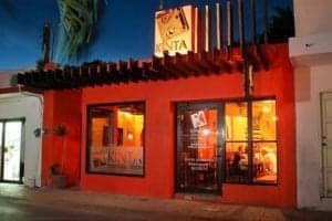 Restaurant exterior at night in Cancun, featuring warm lighting and vibrant orange walls, showcasing ExploreTraveler's focus on local dining experiences.