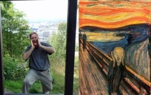 Man mimicking the iconic pose from Edvard Munch's "The Scream," juxtaposed with the famous painting, highlighting Munch's influence on contemporary expressions of art and emotion.