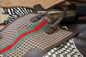 Gucci handbag featuring the iconic GG logo and signature green-red-green stripe pattern, set against a backdrop of luxury fashion materials.