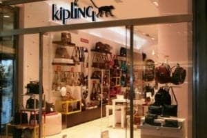 Kipling store front showcasing a variety of bags and accessories, highlighting travel and fashion themes.