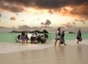 Tourists arriving by boat on a beach in the Galapagos Islands at sunset, highlighting travel experiences in this unique destination.