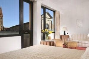 Hotel room at Grand Hotel Minerva in Florence, featuring a bed, seating area, and large windows with views of the city.
