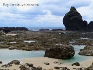 Coastal landscape of Green Island, Taiwan, featuring rocky formations, tidal pools, and a cloudy sky, emphasizing the island's natural beauty.