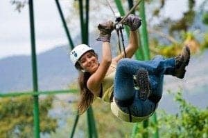 Woman ziplining through lush greenery near Arenal Volcano, showcasing adventure activities in Costa Rica.