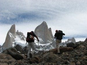 Hikers trekking through rocky terrain with towering mountains in the background, showcasing the stunning natural beauty of El Chaltén, a popular travel destination.