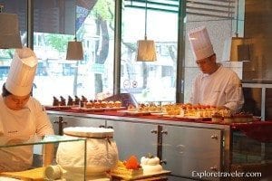 Chefs preparing Asian pastries in a bakery setting, showcasing a variety of colorful desserts and culinary artistry, relevant to ExploreTraveler's focus on Asian cuisine.