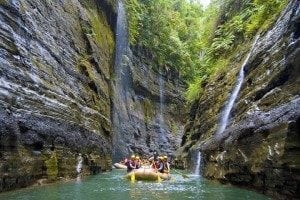 Group rafting in a narrow canyon with lush greenery and waterfalls, showcasing adventure tourism in Beqa.