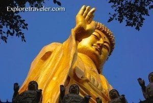 Giant Buddha statue at Fo Guang Shan in Taiwan, golden figure with raised hand, surrounded by smaller statues, blue sky backdrop, symbolizing cultural significance and travel destination.