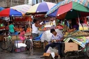 Filipino street market scene with vendors under colorful umbrellas selling fresh fruits and local dishes, highlighting the vibrant culinary culture of the Philippines.
