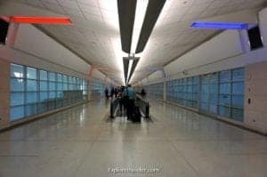 Modern airport corridor with illuminated ceiling lights, showcasing sleek architectural design and glass walls, enhancing travel experience.