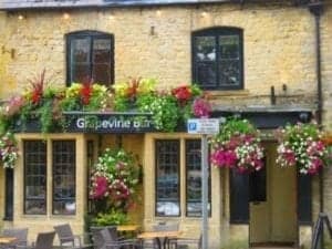 Floral arrangements adorning the exterior of the Grapevine bar in Stow on the Wold, showcasing vibrant colors and inviting atmosphere.