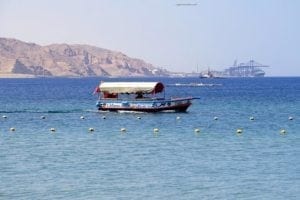 Glass bottom boat on clear waters of the Red Sea, showcasing scenic views and coastal mountains in the background, highlighting unique travel experiences offered by ExploreTraveler.