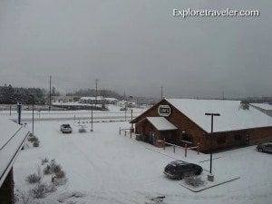 Snow-covered landscape with a wooden building and parked cars, illustrating winter weather conditions relevant to travel insights about blizzards.