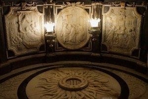 Intricate stone reliefs and ornate lighting fixtures inside the Church of Saint John the Baptist in Carrickmacross, highlighting historical and architectural details.
