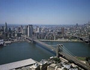 Aerial view of the East River with iconic bridges and Manhattan skyline, showcasing urban landscape and travel destination highlights.