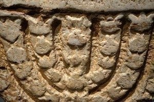 Ancient stone relief featuring a menorah, symbolizing Jewish heritage and culture, relevant to the Israel Museum's Hanukkah celebrations.