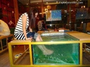 Billiard room featuring a woman sitting at a table with a fish spa, highlighting unique travel experiences related to leisure and relaxation.