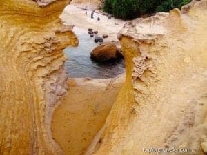 Yehliu Geopark landscape featuring unique geological formations, sandy beach, and visitors exploring natural rock structures.