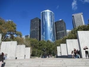 Castle Clinton National Monument in Battery Park, New York City, surrounded by modern skyscrapers and visitors, showcasing its historical significance amidst a contemporary urban landscape.