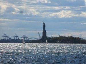 East Coast Memorial in Battery Park, New York City, with the Statue of Liberty in the background, surrounded by water and boats, symbolizing tribute to military service.