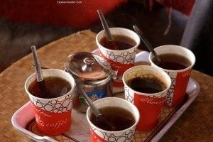 Tray of five cups of instant coffee with spoons, alongside a small teapot, reflecting Bedouin coffee culture in the Jordanian deserts.
