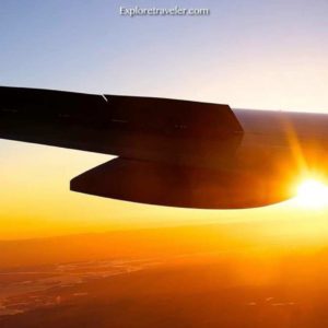 Airplane wing silhouetted against a vibrant sunset, symbolizing travel and exploration for beach destinations on ExploreTraveler.