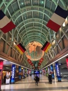 Interior view of Chicago O'Hare International Airport showcasing colorful flags, modern architecture, and travelers, highlighting the airport's amenities and vibrant atmosphere.