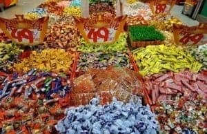 Colorful assortment of candies and sweets arranged in vibrant sections, showcasing diverse flavors and packaging, representing global culinary delights for food enthusiasts.