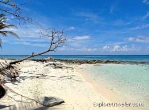 Caribbean beach scene with clear turquoise water, sandy shore, and a sunlit sky, representing travel inspiration for ExploreTraveler.