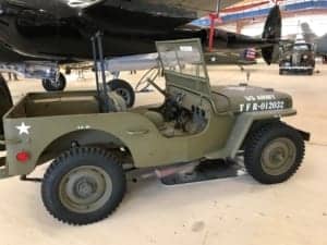 A car parked in front of a military vehicle - Jeep