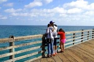 Fun In The Sun At Oceanside California USA - A group of people sitting on a bench next to a body of water - Ocean