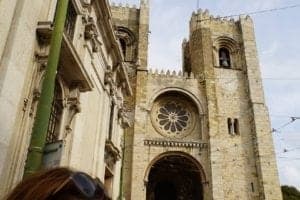 Lisbon Cathedral exterior featuring intricate stonework, large rose window, and two prominent towers, highlighting its historical and architectural significance in Lisbon, Portugal.
