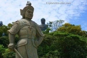 Discovering The Sights And Scenes Of Hong Kong - A statue of a man with Ghibli Museum in the background - Tian Tan Buddha