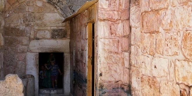 The Church Of The Nativity In Bethlehem Israel - A stone building that has a sign on a brick wall - Church of the Nativity