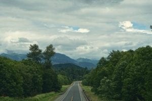 Scenic view of a winding road leading through lush greenery with Mount Scenery in the background, capturing the beauty of the Northern Cascades in Washington State.