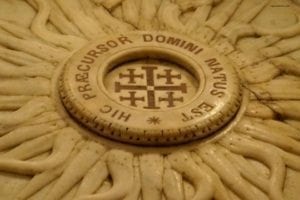 Intricate stone design featuring a central inscription "HIC PRÆCURSOR DOMINI NATUS EST" and cross motifs, symbolizing the Church of Saint John the Baptist in Ein Karem, Jerusalem.