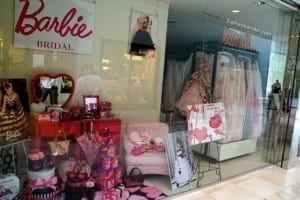 Barbie bridal shop display featuring pink wedding dresses, accessories, and themed merchandise, showcasing a blend of fashion and nostalgia.