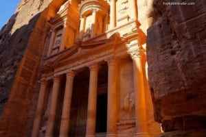 Petra's iconic Al-Khazneh (The Treasury) illuminated by sunlight, surrounded by towering rock formations, showcasing Jordan's ancient architectural marvels for travel enthusiasts.