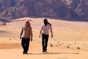 Two men walking in the desert landscape of Jordan, showcasing the natural beauty and vastness of the region, relevant to ExploreTraveler's photo tour guide.