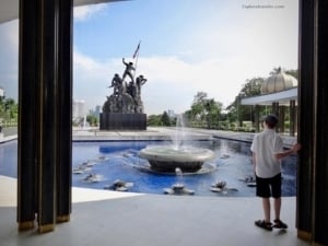 Boy standing by a fountain in front of a statue, showcasing Malaysia's cultural heritage and scenic beauty at an attraction featured in ExploreTraveler's travel article.